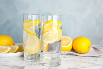 Soda water with lemon slices on white marble table