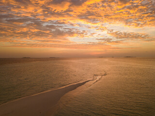 Aerial spherical panorama of tropical paradise beach on tiny Maldives island. Clouds in red and orange during sunset.