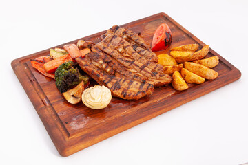 Delicious barbecued ribs on wooden cutting board, served with grilled vegetables