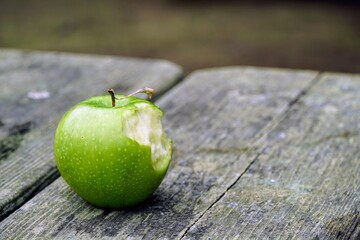 Apple with bite taken out of it on an old wooden table
