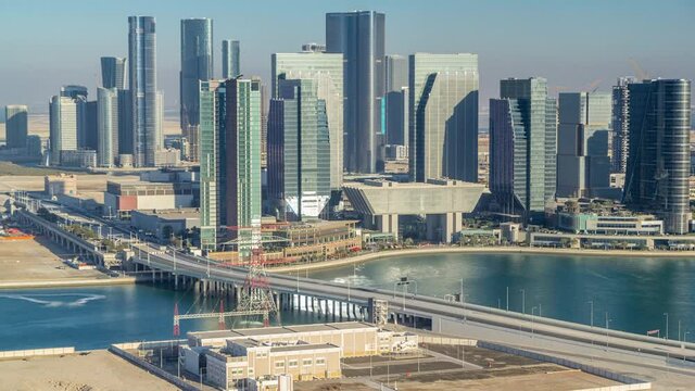 Aerial skyline of Abu Dhabi city centre from above timelapse before sunset with shadows from skyscrapers. Bridge and traffic on the road