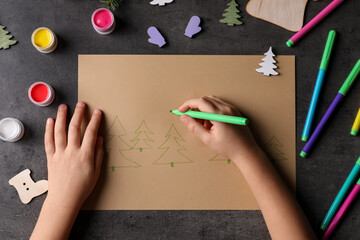 Little child making Christmas card at black table, top view