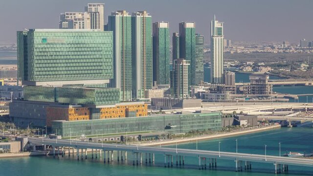 Aerial skyline of Abu Dhabi city centre from above timelapse before sunset with shadows from skyscrapers. Bridge and traffic on the road