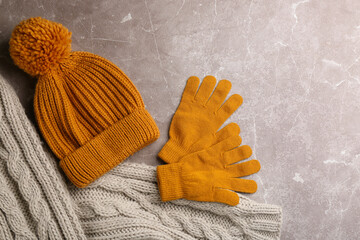 Stylish gloves, scarf and hat on light grey marble table, flat lay