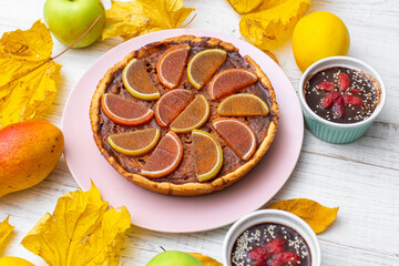 Pumpkin pie on a white wooden background. Yellow autumn leaves, apples and pears.