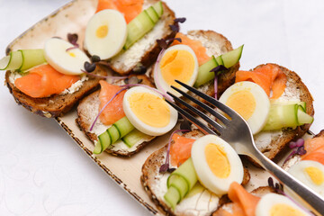 bruschetta with cheese, cucumber, salmon and boiled egg on a plate,