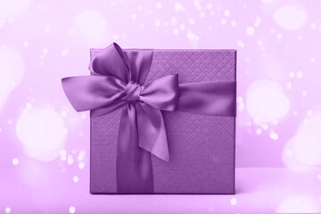 Purple gift with satin ribbon on background with bokeh lights. Christmas. Birthday. Happy woman's day. Mothers Day. Valentine's Day. Front view.