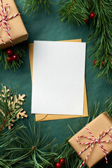 Christmas greeting card mockup with gift boxes and pine tree branches on green paper background