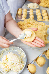 Producing classic croissants at the bakery shop. Woman is rolling dough into rolls for further baking. French pastry goods.