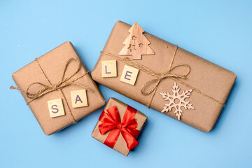 Christmas background with gifts in craft paper and a Christmas tree on a blue background. Discounts...
