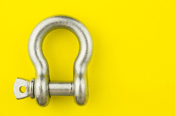 Steel rigging shackle on yellow background with space for text.