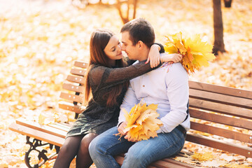 Couple in love sits on a park bench in autumn and talks cute
