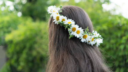 A young woman with beautiful shining brown long hair is walking in the Park. On her head is a...