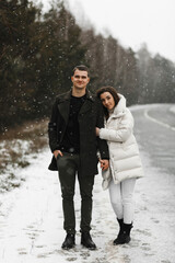 Fototapeta na wymiar Lovely man and woman at the background of the winter forest with place for your text. Love, relationship, winter holidays. Winter couple photo ideas