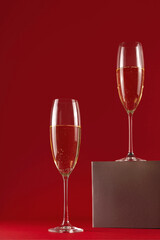 Two glassess of champagne on a stand on a red background. Holiday and New Year concept. 
