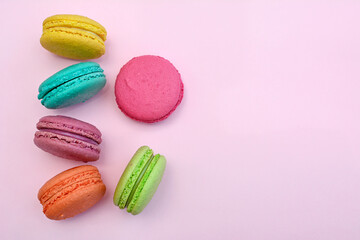 Fototapeta na wymiar Close-up of colored macaroon on a pink background. View from above