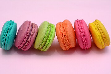 Multicolored macarons on a pink background, close up.