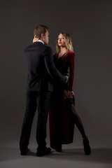 Affectionate young couple in elegant outfits dancing in studio