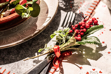 Christmas festive table decoration close up with festive cutlery decorated with flowers and berries. .
