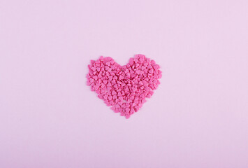 Hundreds of tiny pink heart-shaped hearts lie in the shape of a large heart as a symbol of romantic love