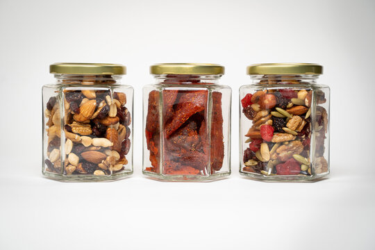 Frascos de cristal con nueces, almendras, cacahuates, pasas, golosinas mason jar fondo blanco