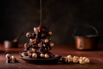 melted chocolate poured on overlapping pieces of dark chocolate with hazelnuts Still life