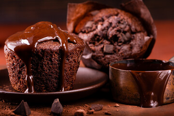 Foreground muffins covered with melted dark chocolate. Composition and dark brown background. Still...