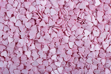 the pink surface is covered with lots of heart-shaped pink confetti as a romantic background composition