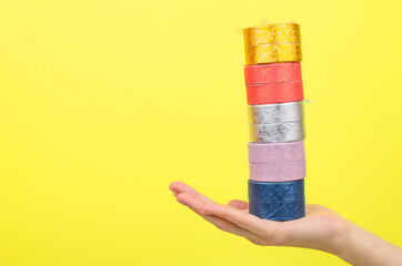 Multicolored gift boxes in a female hand on a yellow background