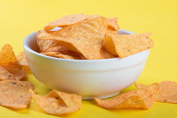 Nachos in a white bowl with yellow background.
