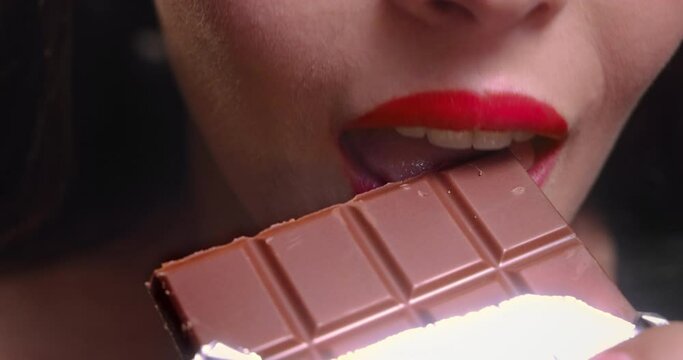 Young woman mouth biting chocolate bar