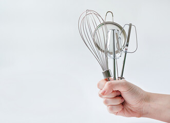 Woman hand holding kitchen utensils on grey background with copy space