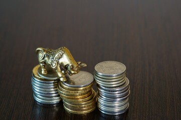 Metal bull with coins on the table. Financial symbol.