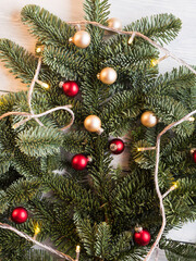 Christmas spruce branches with red golden decor ang holiday lights on wooden wood table. Festive background