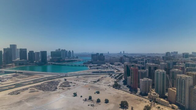 Aerial skyline of Abu Dhabi city centre from above timelapse during all day until sunset with shadows from skyscrapers mooving very fast.