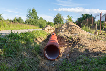 corrugated plastic pipe in orange color for the entrance lies in the ditch
