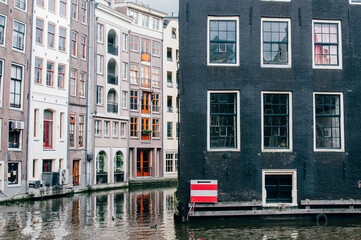 Fototapeta na wymiar Classic houses located in a canal in Amsterdam The Netherlands iwith a red and white signal with an arrow