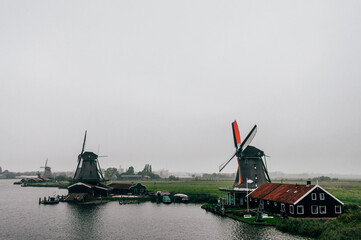 Several windmills  in a dark and cloudy day in Zaanse Schans  The Netherlands with fog
