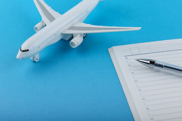 flight planning concept. plane, diary and pen on a blue background. list of things for the trip. planning business meetings in different cities. businessman daily routine.