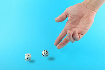 hand throws dice on blue background