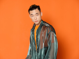 Asian man wearing orange t-shirt over isolated background and gray jacket model