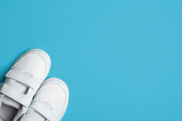 Child's new white sport shoes or sneakers on the light blue pastel background.