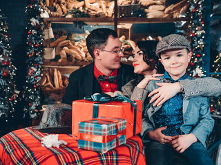 Happy family on the eve of New Years and Christmas. Christmas scene of loving parents and their son dressed in retro style.