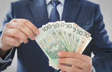 Man in a suit counts Polish banknotes