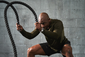 Black man training with battle ropes in crossfit