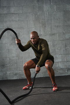 Black man training with battle ropes in crossfit