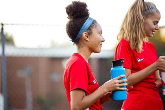 Female soccer players drinking water on field