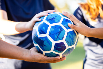 Soccer team hands huddled on ball