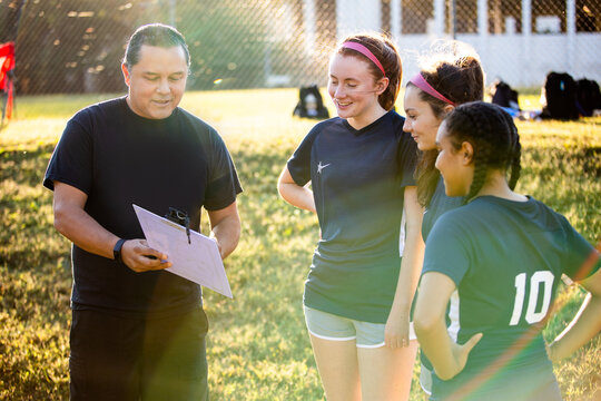 Teenage soccer coach teaches plays with female team