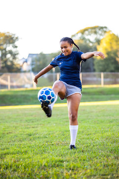 Mixed race female soccer player kicking ball